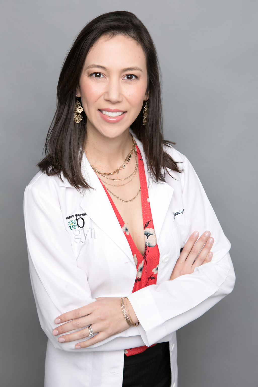 Asian woman in her white lab coat smiling with her arms crossed in front of her